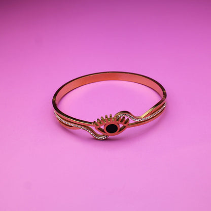 Rose gold bracelet with a black gemstone on a pink background