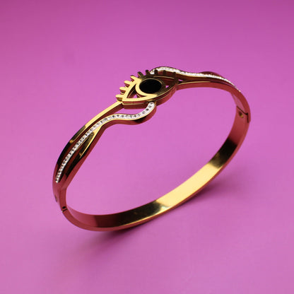 Gold ring with a green gemstone on a pink background