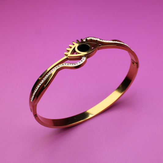 Gold ring with a green gemstone on a pink background