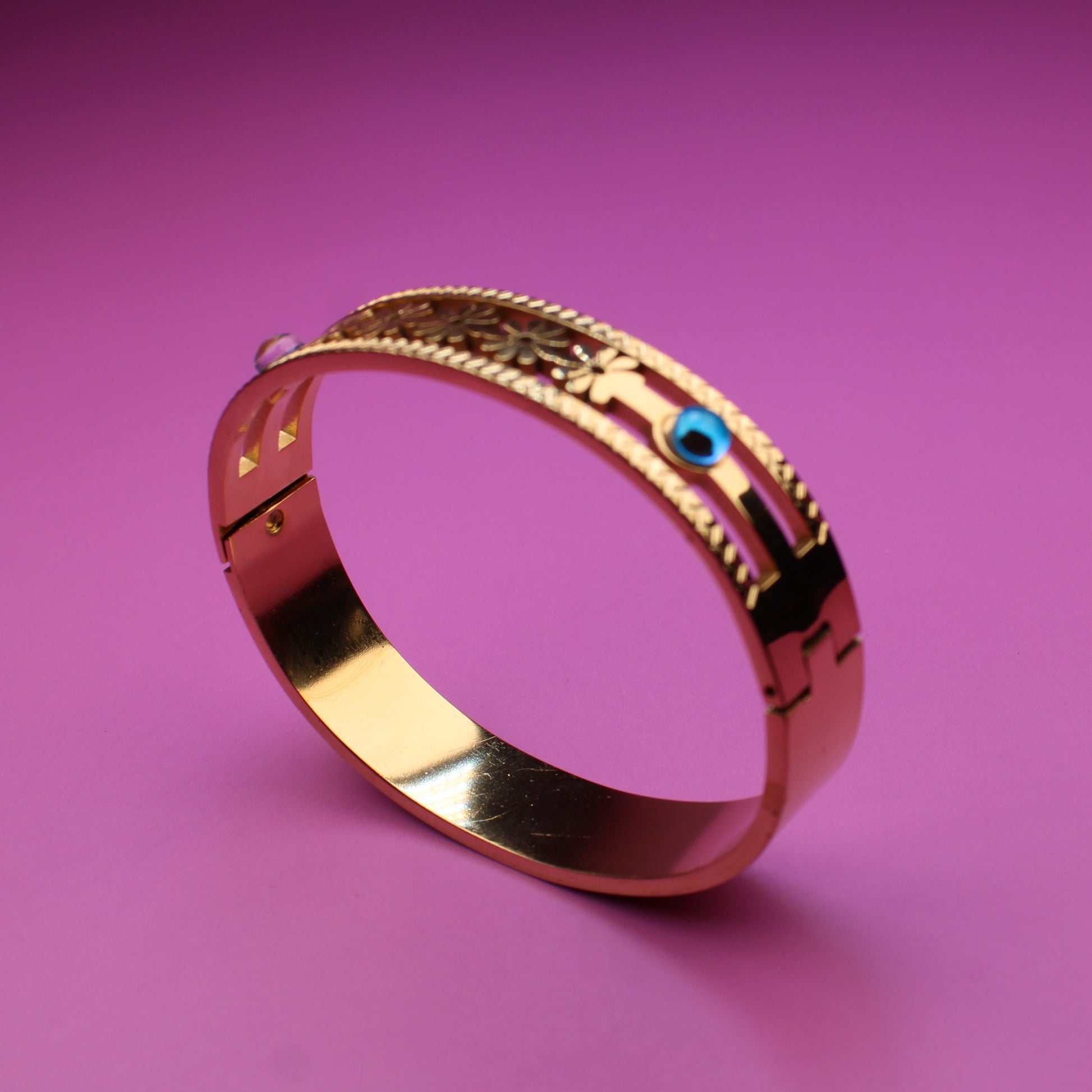 Gold bracelet with a blue gemstone on a pink background