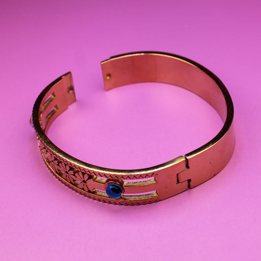 Copper bracelet with engraved design on a pink background