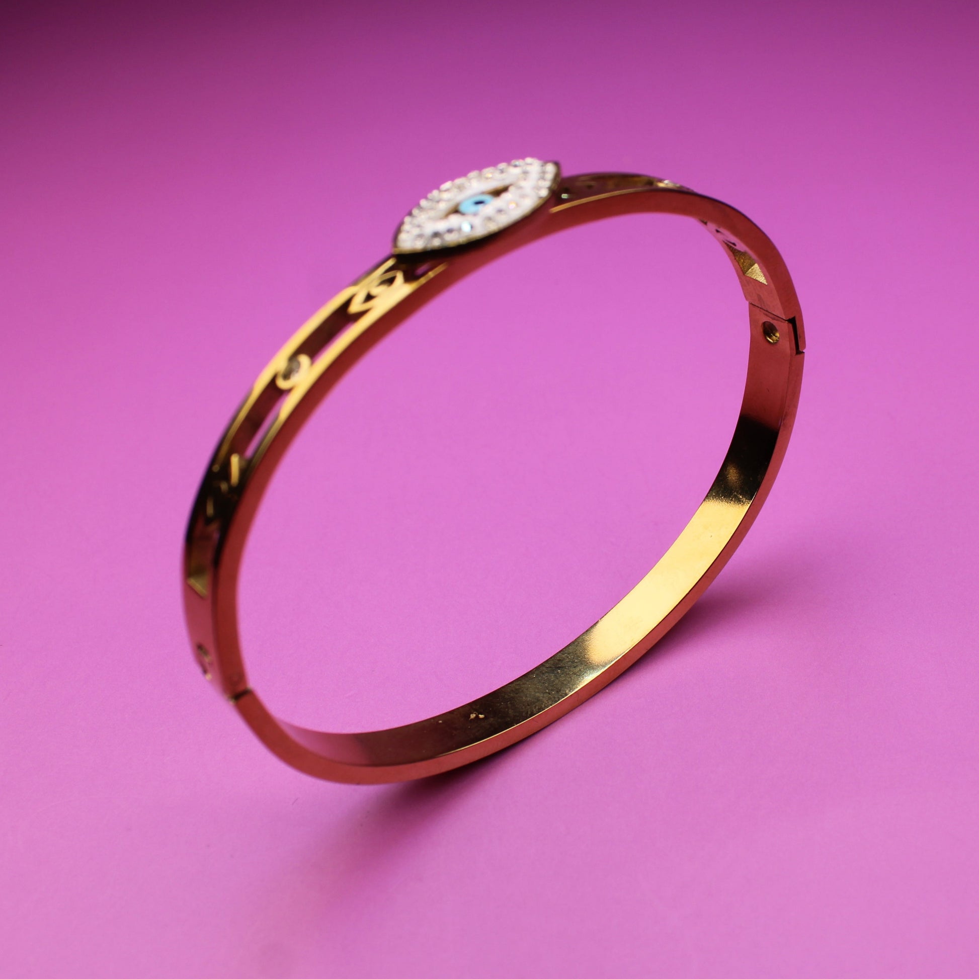 Gold bracelet with a diamond on a pink background