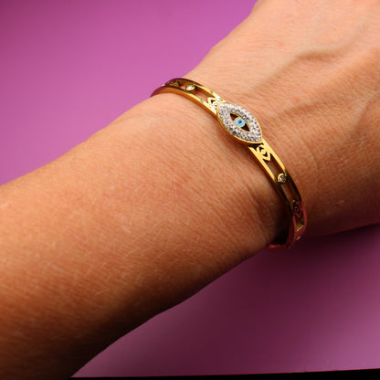 Hand wearing a gold bracelet on a purple background