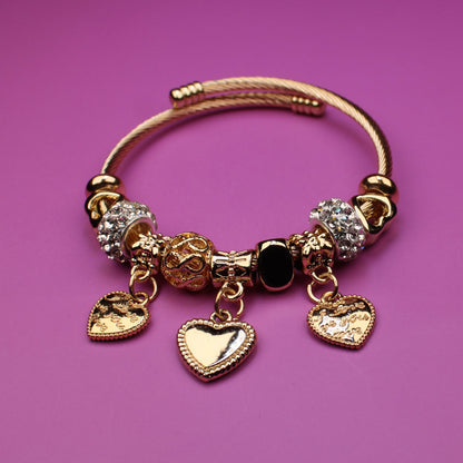 Gold bracelet with charms on a pink background