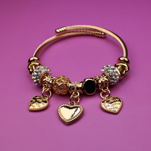 Gold bracelet with charms on a pink background
