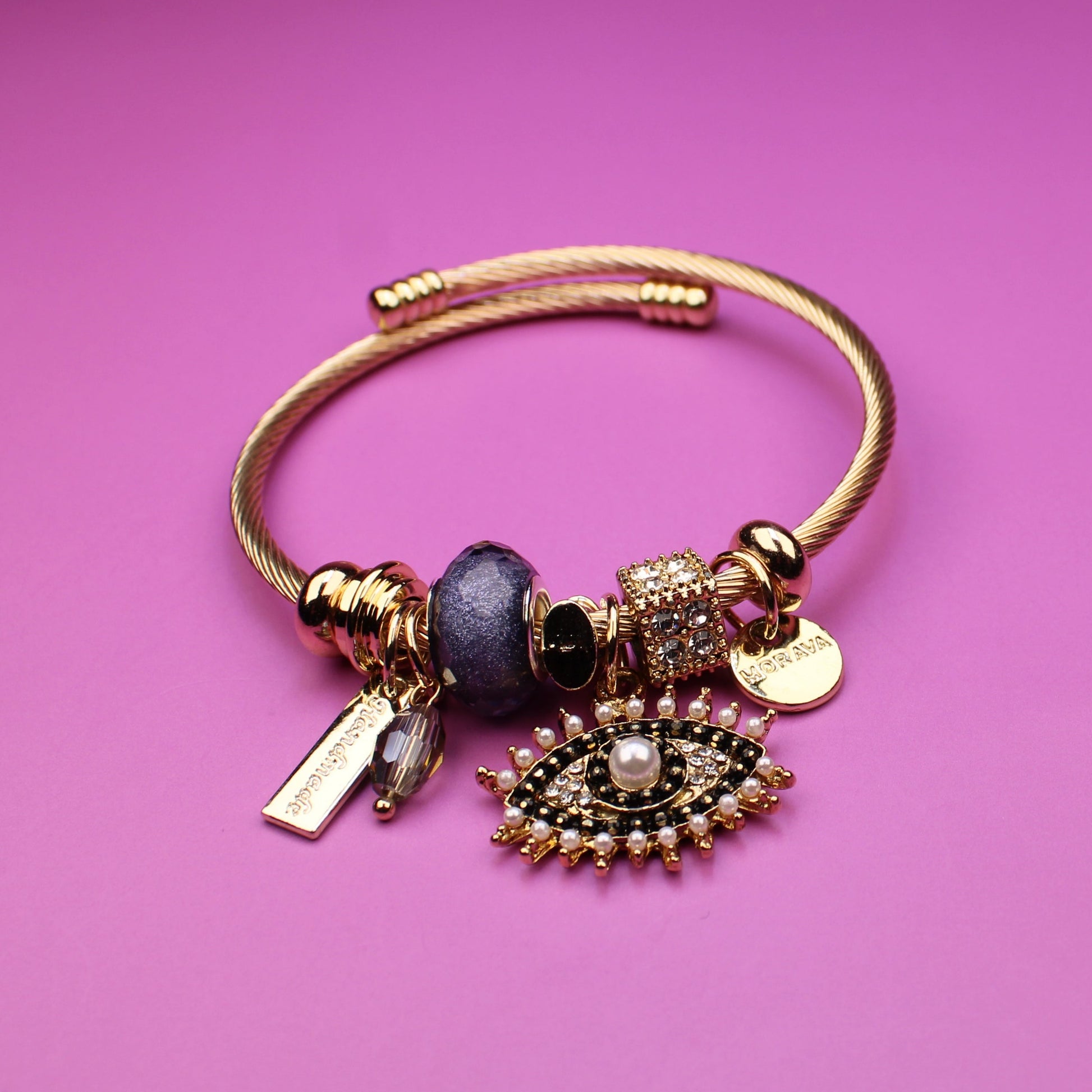 Gold bracelet with charms on a pink background
