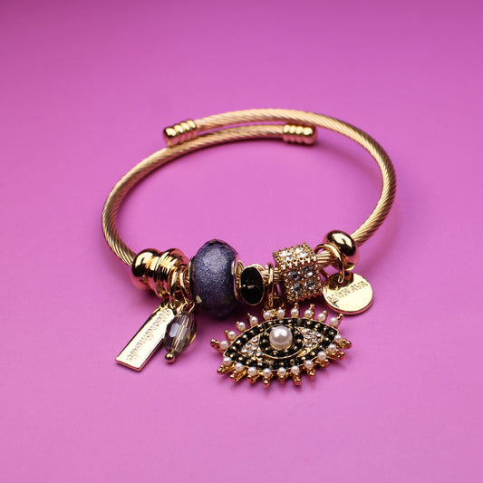 Gold bracelet with charms on a pink background
