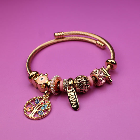Gold bracelet with charms on a pink background
