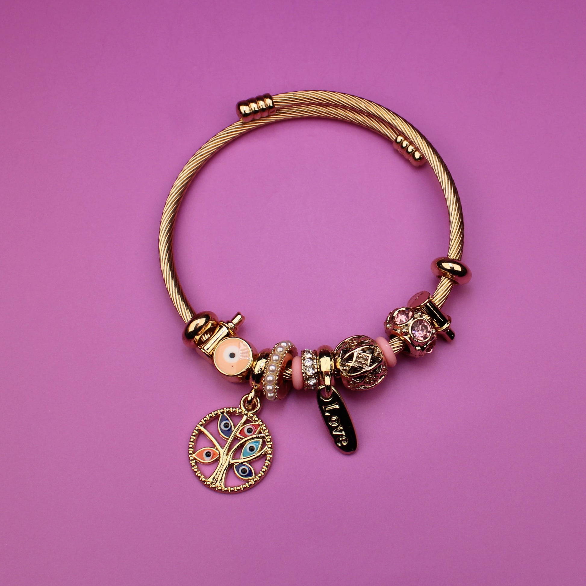Gold bracelet with charms on a pink background
