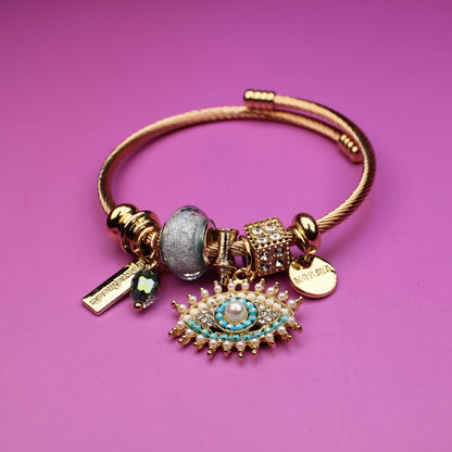 Gold bracelet with charms on a pink background