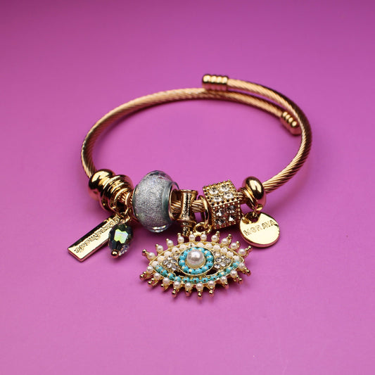 Gold bracelet with charms on a pink background