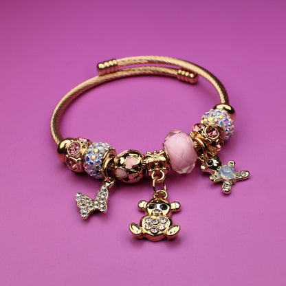 Gold bracelet with charms on a pink background