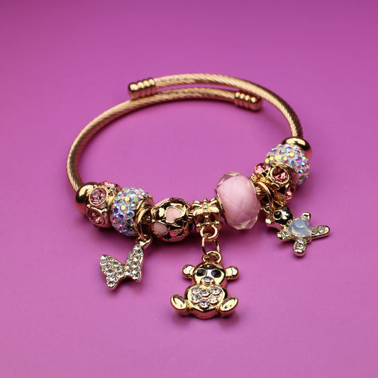 Gold bracelet with charms on a pink background
