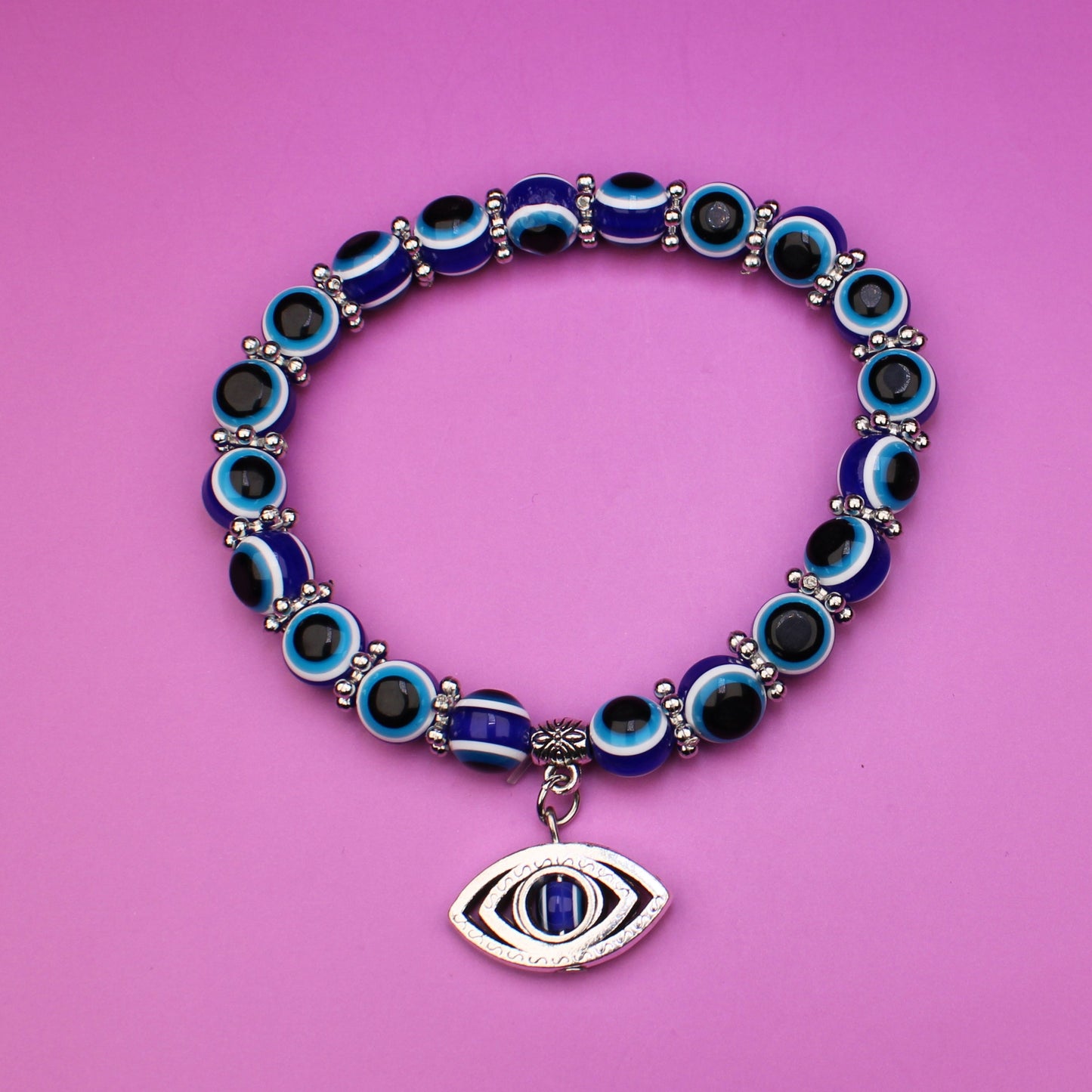 Bracelet with blue beads and an eye charm on a pink background