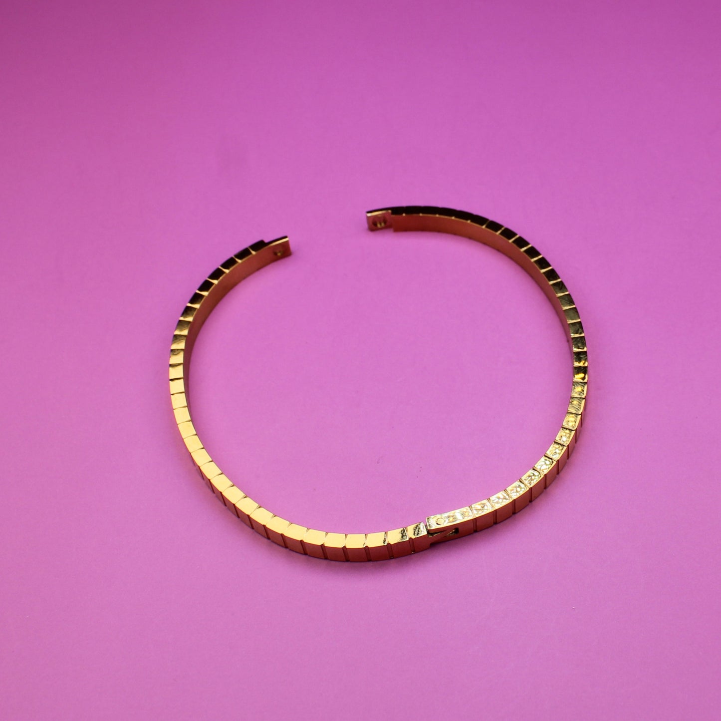 Gold bracelet on a pink surface