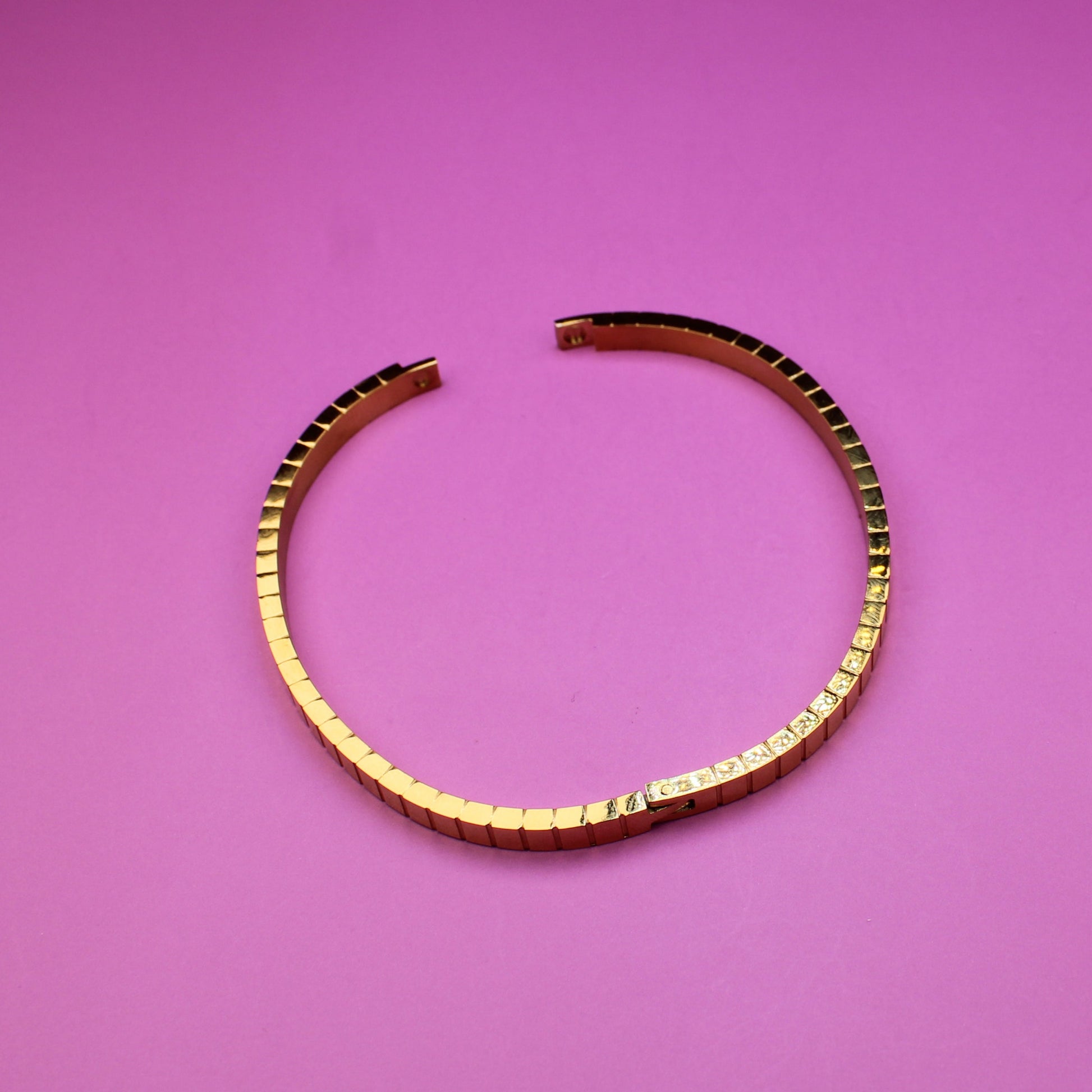 Gold bracelet on a pink surface