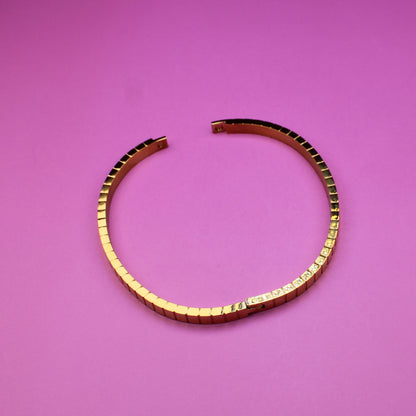 Gold bracelet on a pink surface
