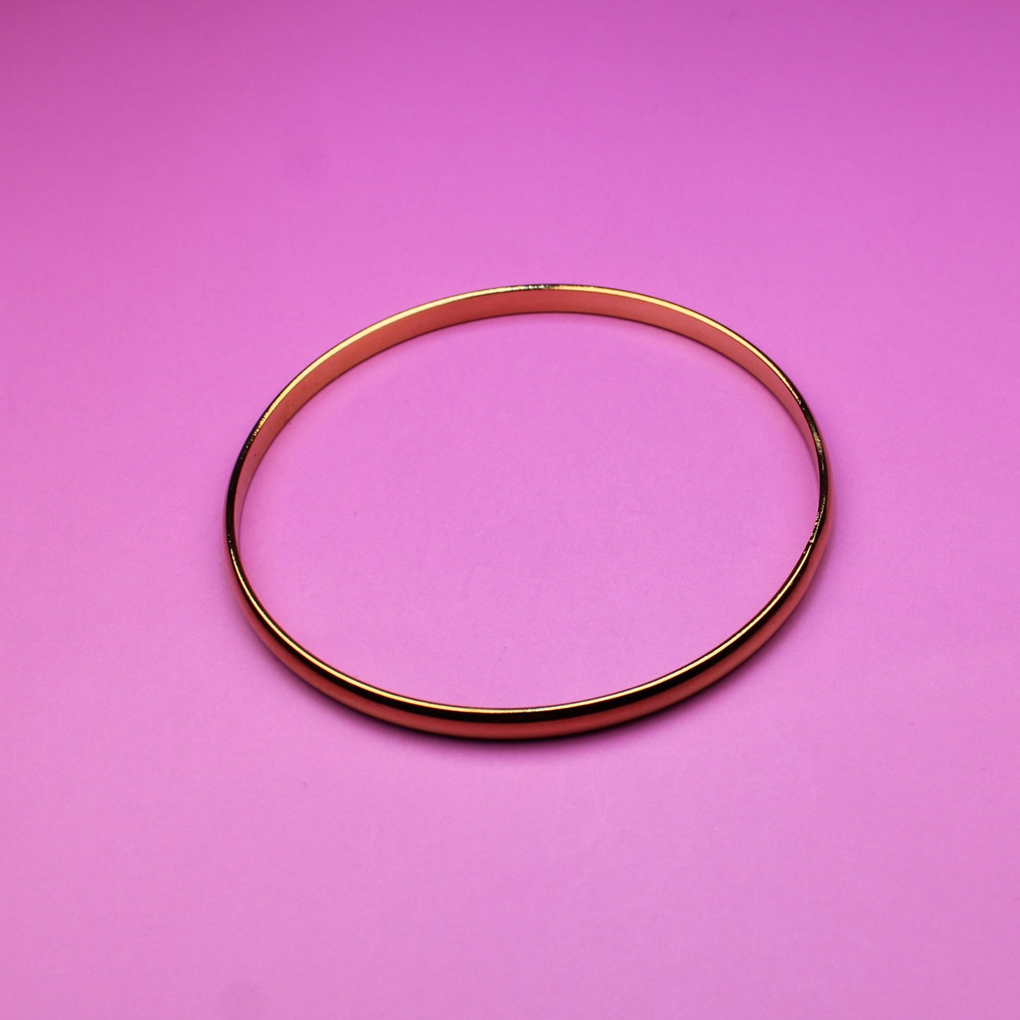 Gold bracelet on a pink background