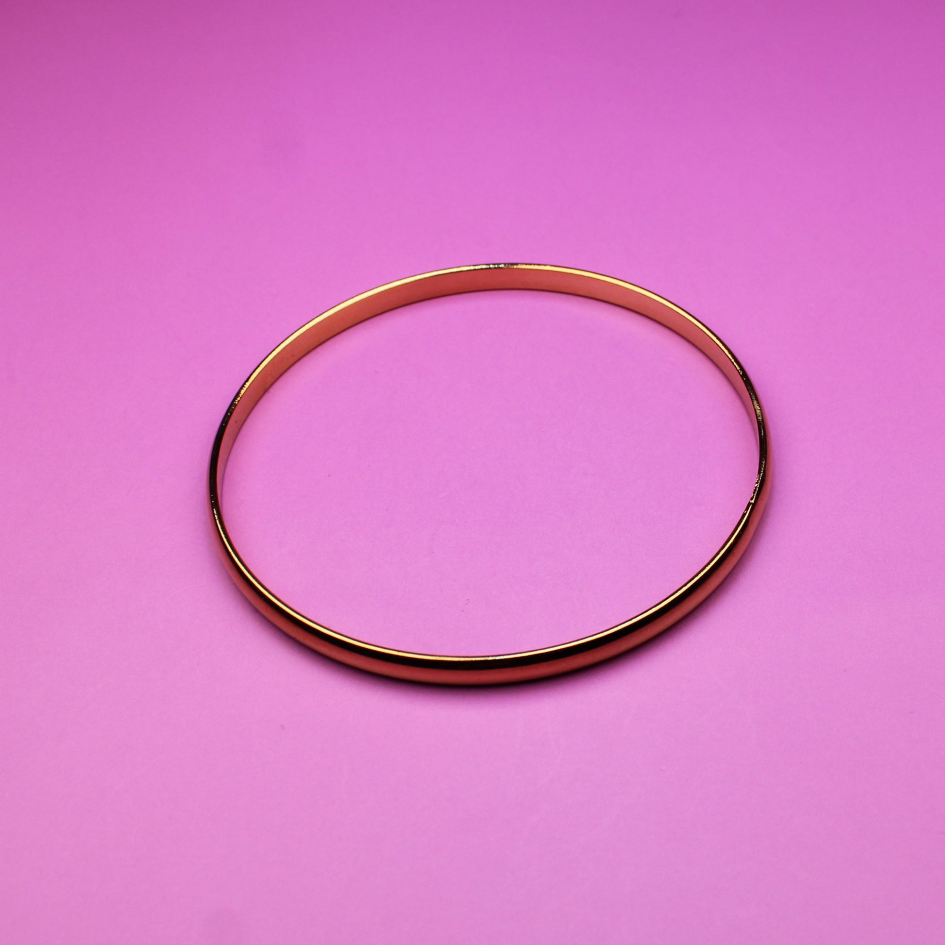 Gold bracelet on a pink background