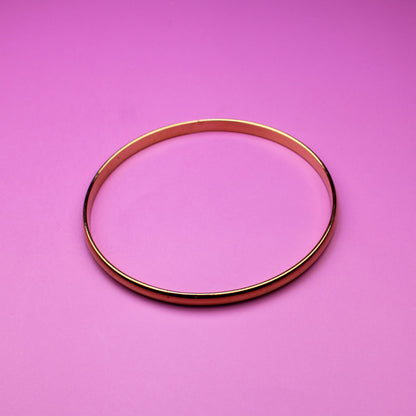 Gold bracelet on a pink surface