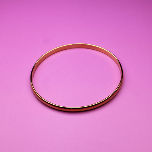 Gold bracelet on a pink surface