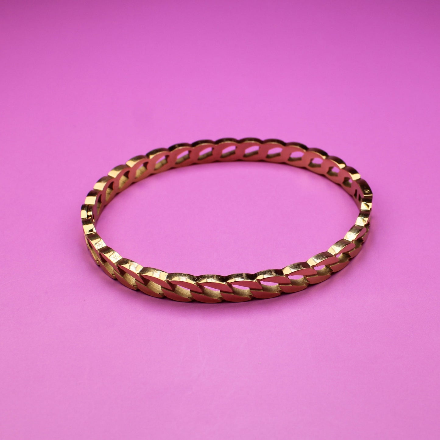 Gold bracelet on a pink background