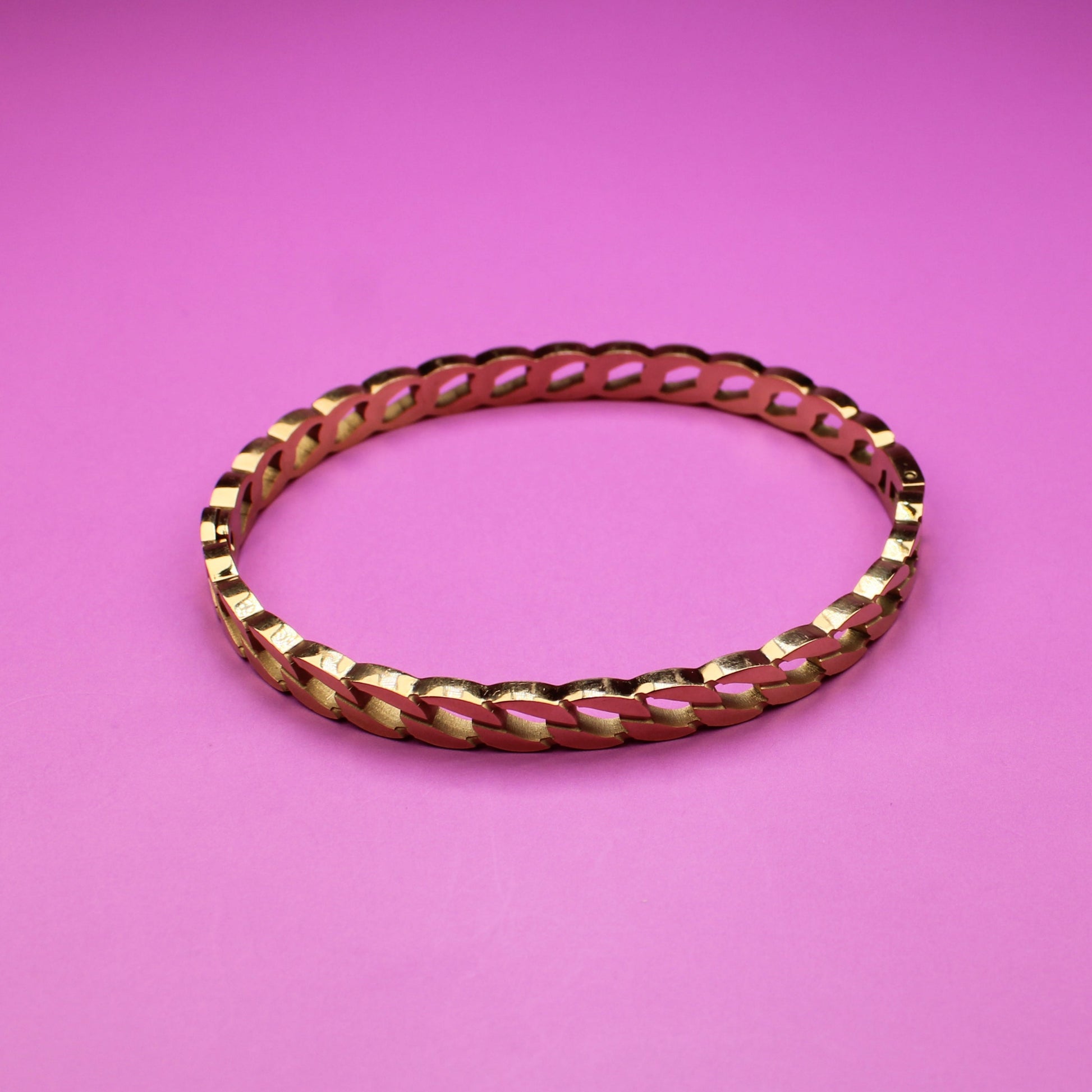 Gold bracelet on a pink background