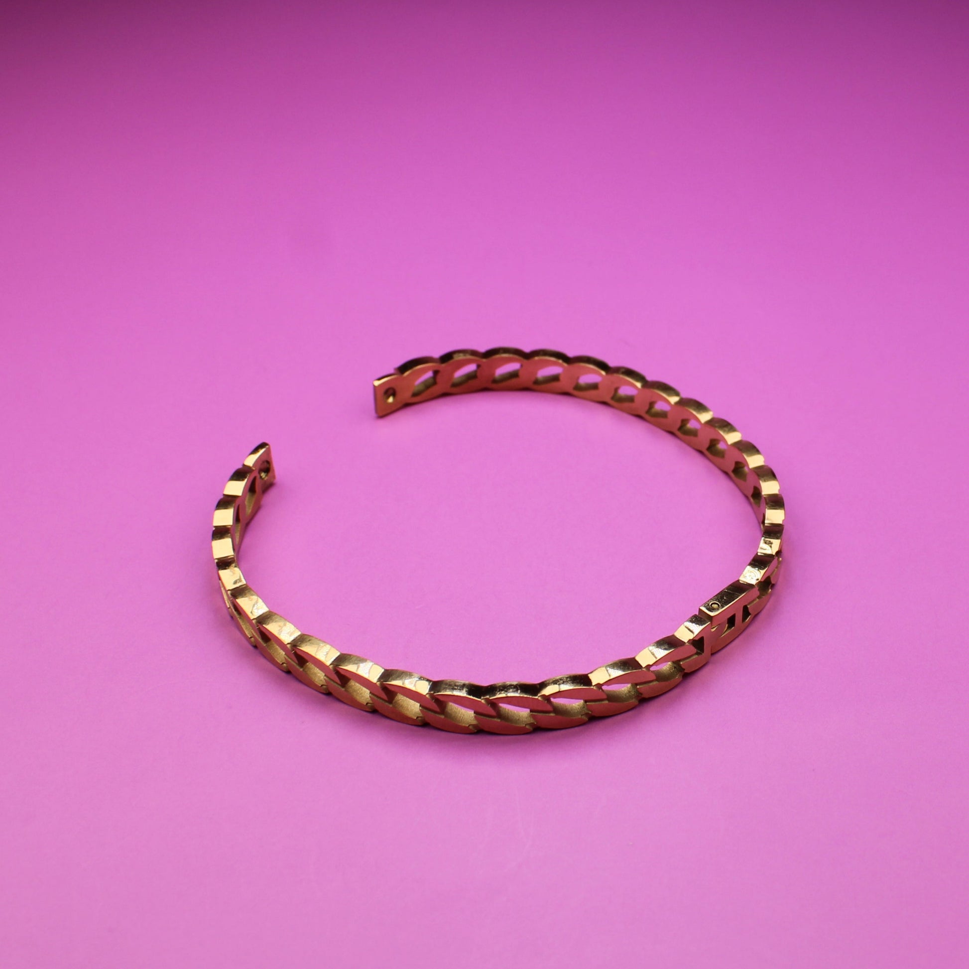 Gold bracelet on a pink background