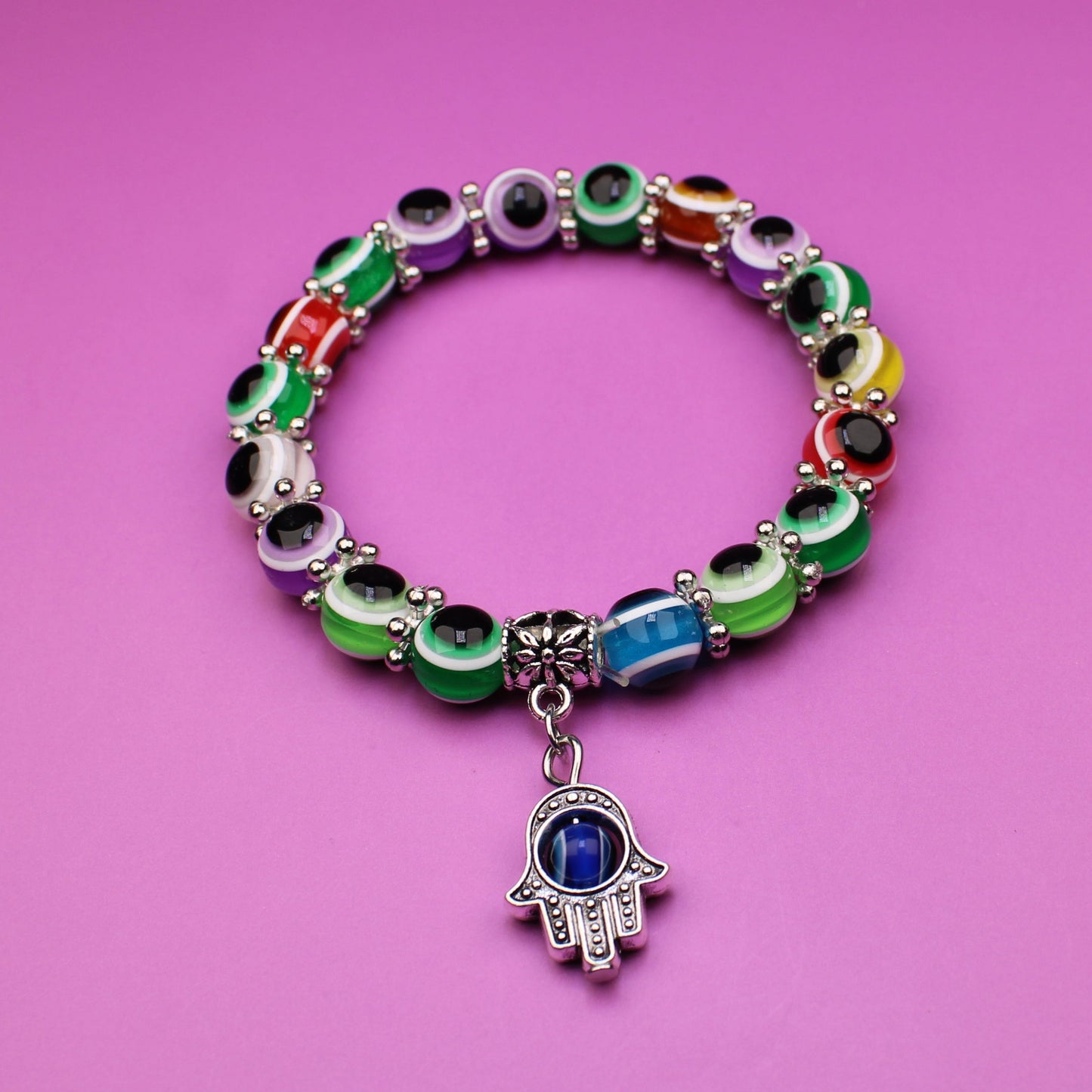 Colorful bracelet with a hamsa charm on a pink background