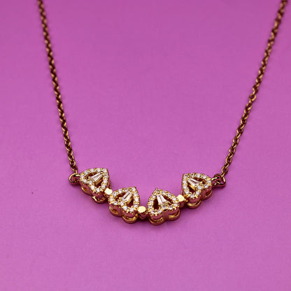 Gold necklace with heart-shaped pendants on a pink background