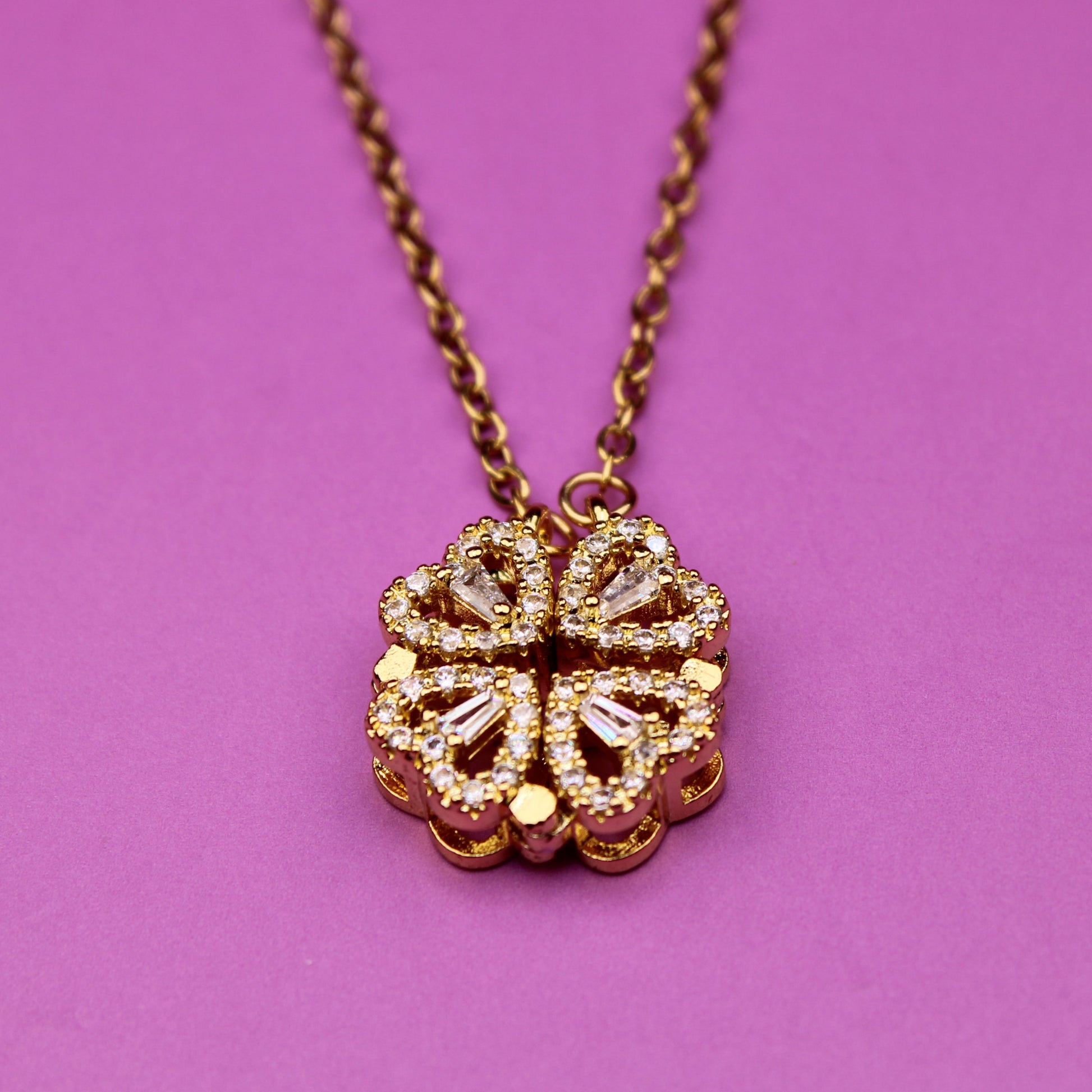 Gold necklace with a floral pendant on a pink background