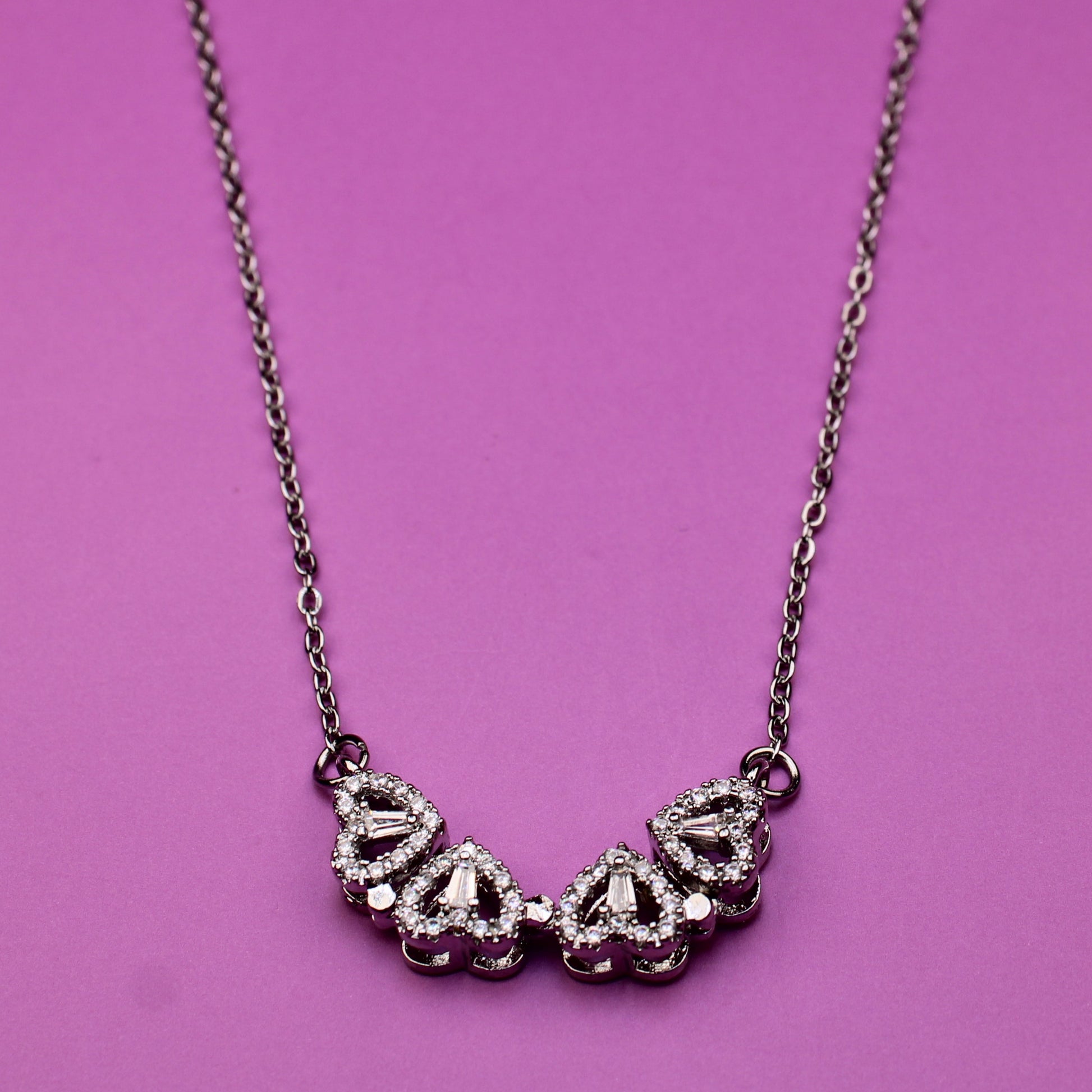 Silver necklace with floral design on a pink background