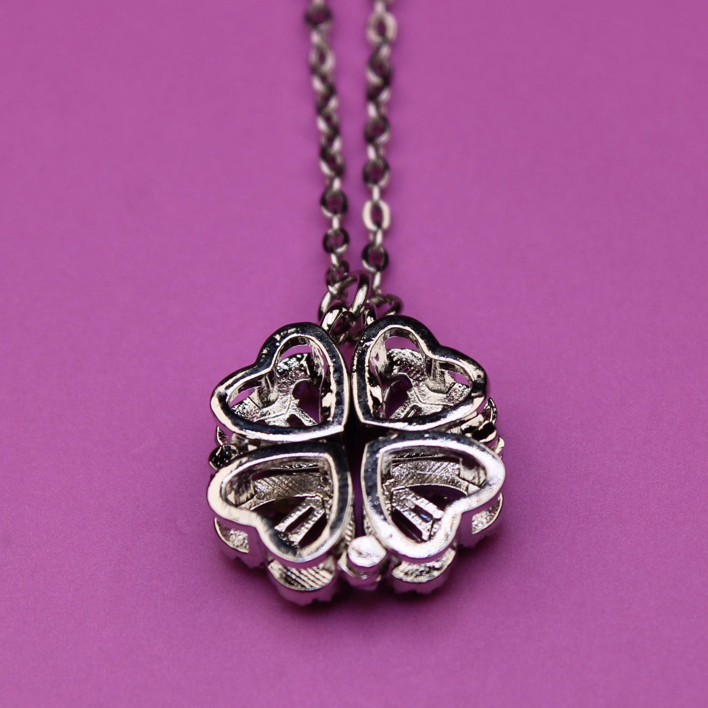 Silver four-leaf clover pendant necklace on a purple background