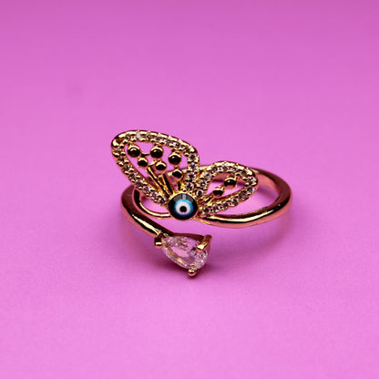 Gold butterfly ring with a pink gem on a pink background