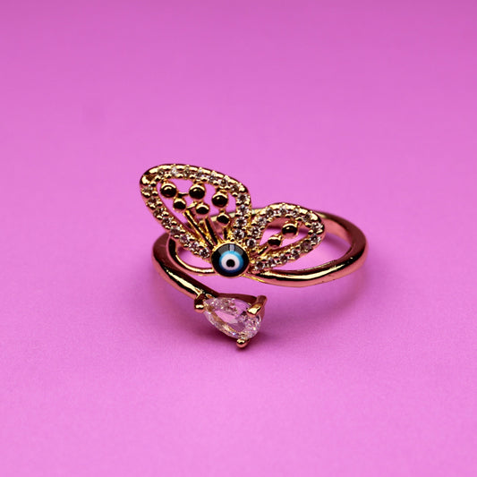 Gold butterfly ring with a pink gem on a pink background