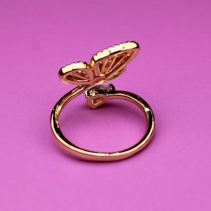 Gold butterfly ring on a pink background