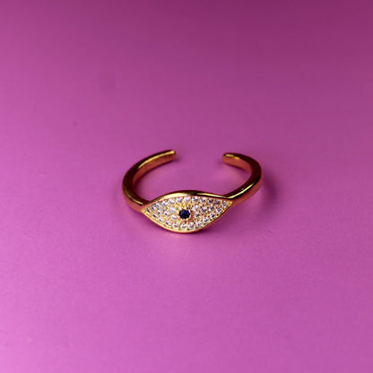 Gold open ring with a small gemstone on a pink background