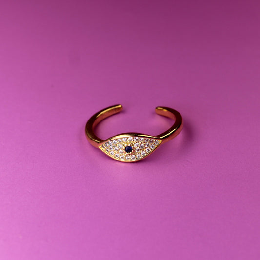 Gold open ring with a small gemstone on a pink background