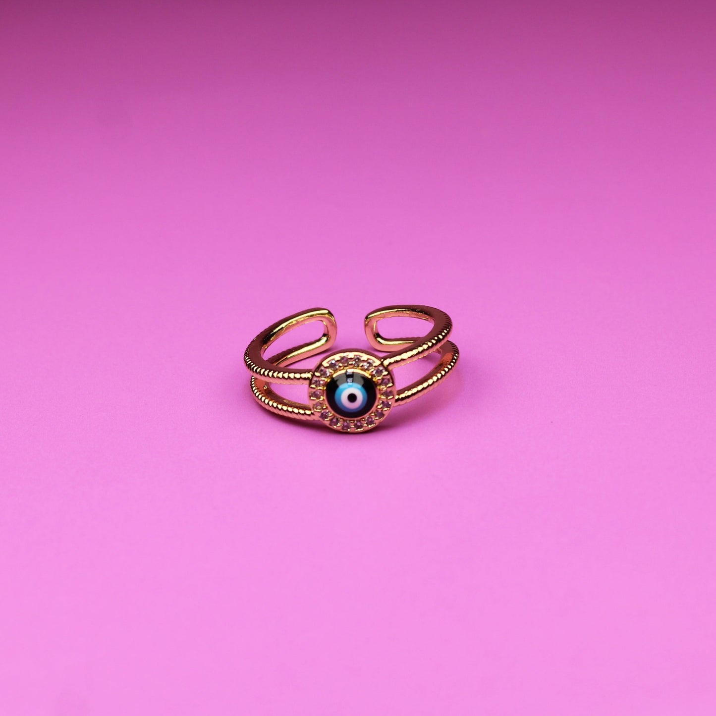 Gold ring with a green gemstone on a pink background