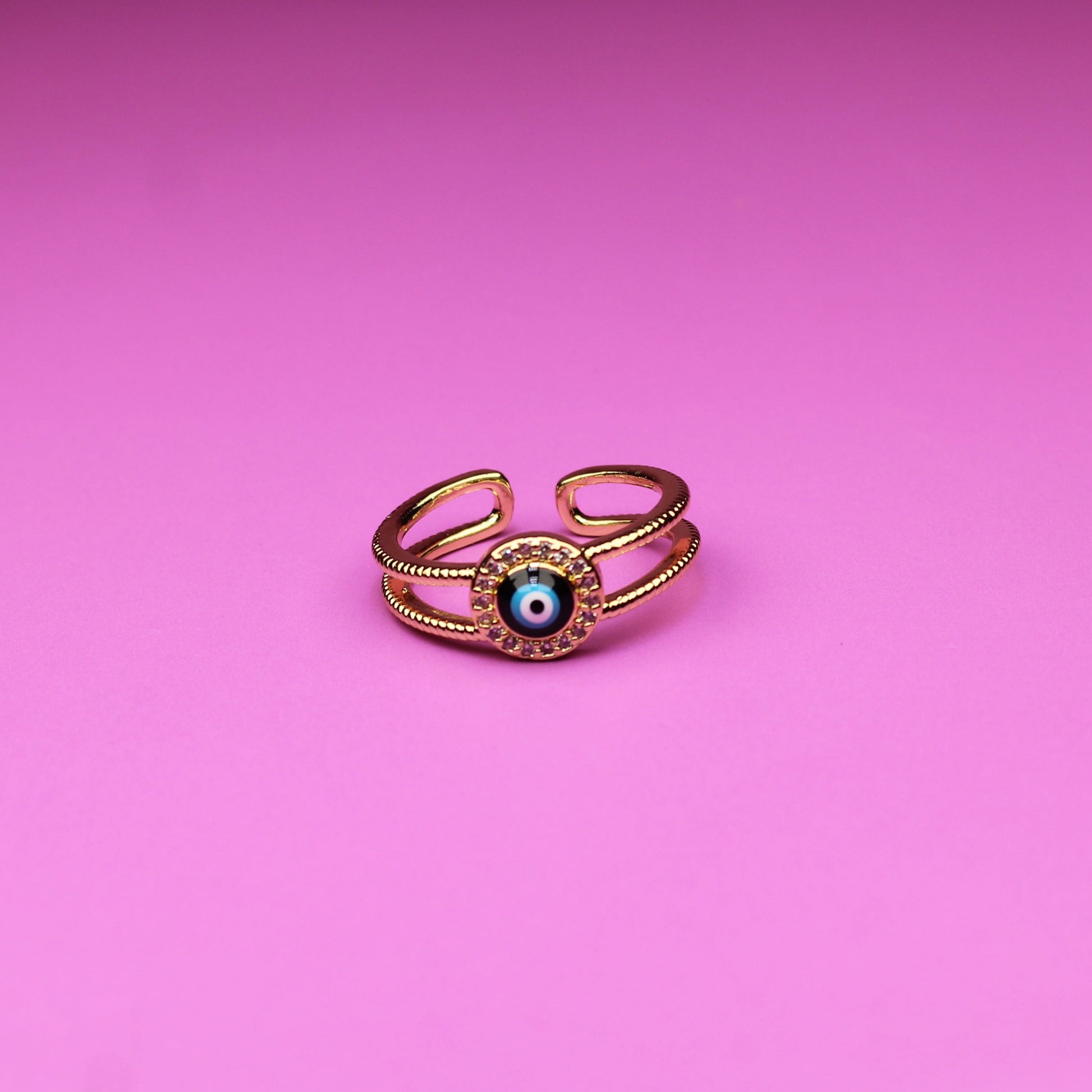 Gold ring with a green gemstone on a pink background