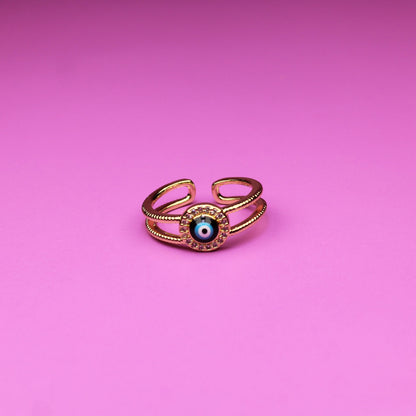 Gold ring with a green gemstone on a pink background