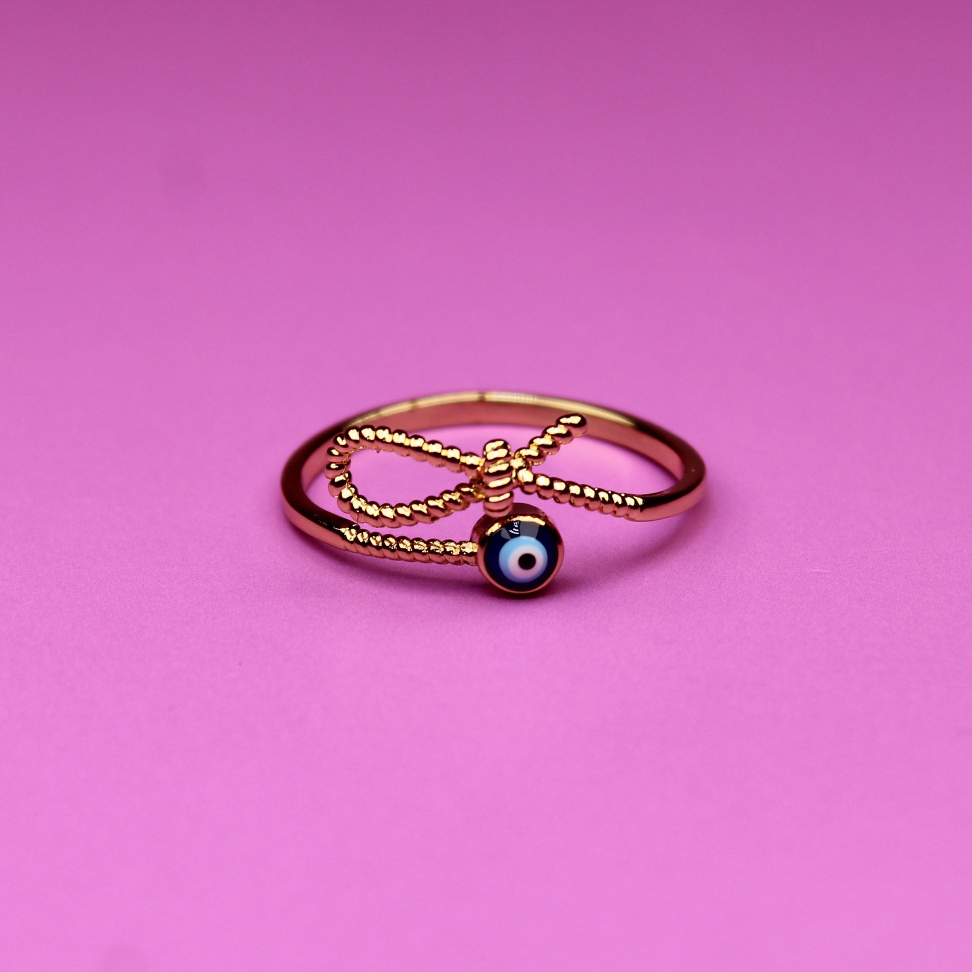 Gold ring with a blue gemstone on a pink background