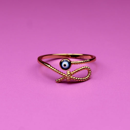 Gold ring with a black gemstone on a pink background