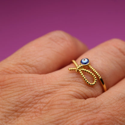 Gold ring with a blue gemstone on a hand against a purple background