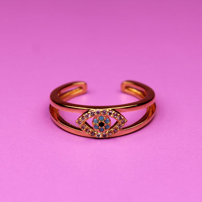 Gold bracelet with a colorful gemstone on a pink background