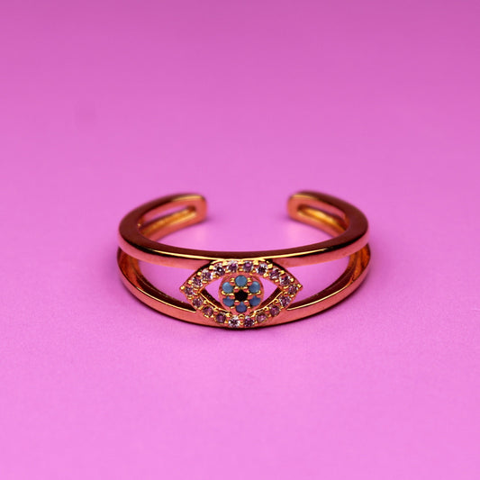 Gold bracelet with a colorful gemstone on a pink background