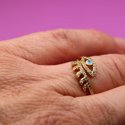 Gold ring with a blue gemstone on a person's finger against a pink background