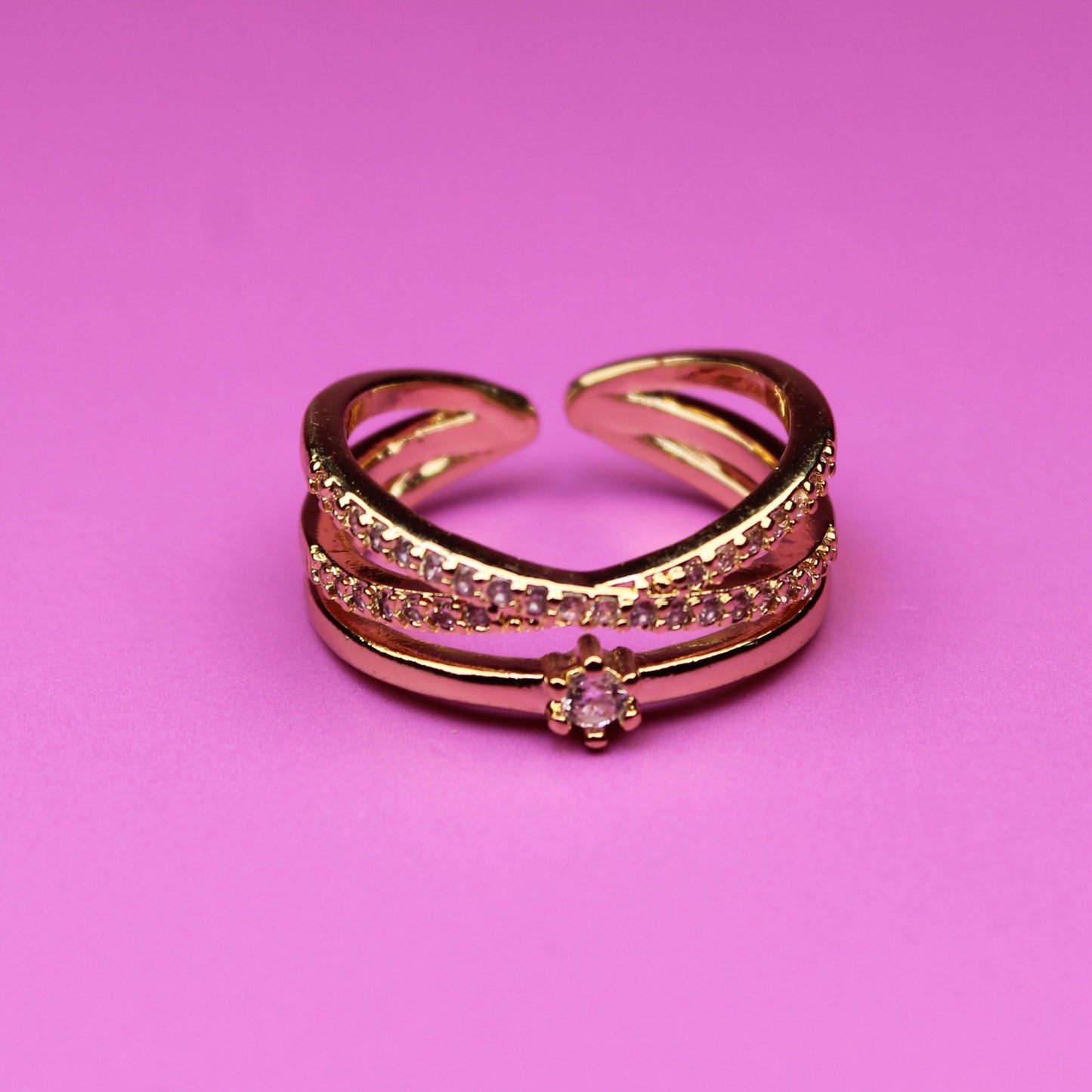 Rose gold ring with gemstones on a pink background