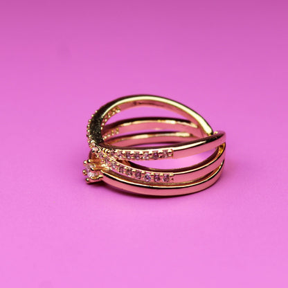 Gold ring with embedded stones on a pink background