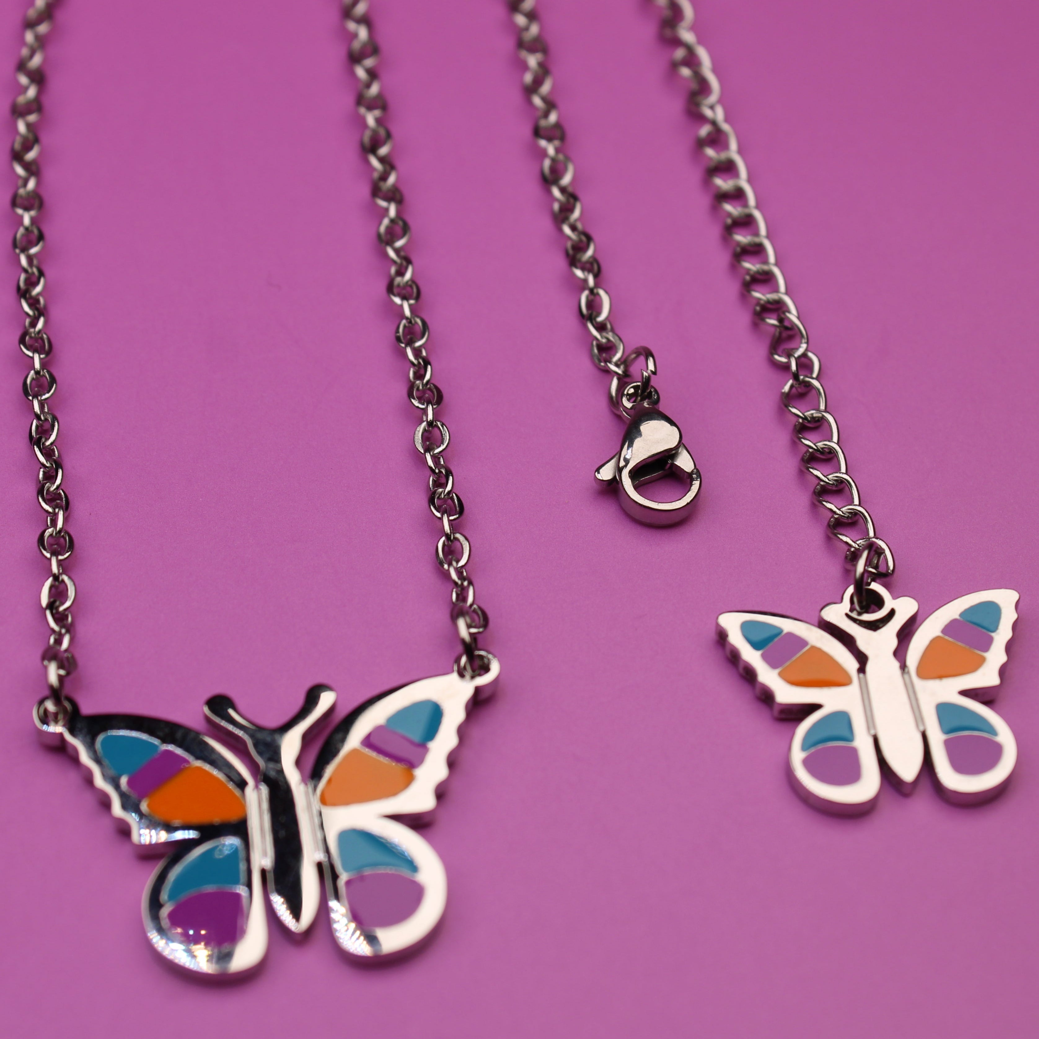 Butterfly-shaped necklace with colorful wings on a purple background